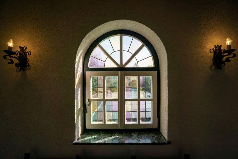 Bogenfenster aus Holz mit Sprossenteilung und buntem Struktu