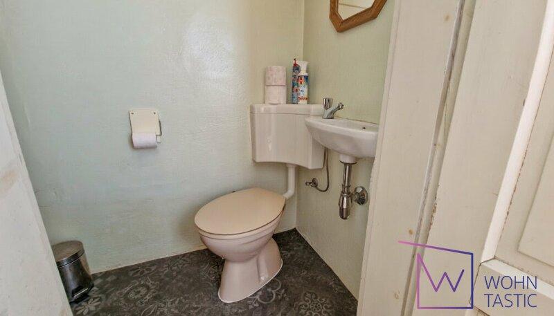 WC mit Fenster diskret hinter einer Tapetenwand.